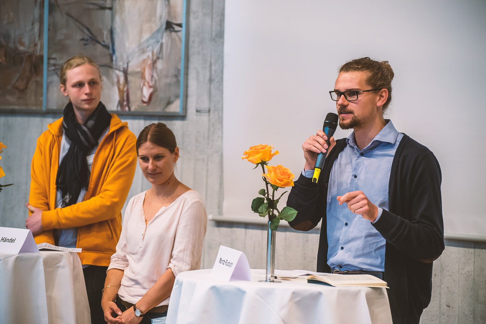 Zwei junge Männer und eine junge Frau bei einer Diskussion im Festsaal der Evangelischen Akademie Bad Boll
